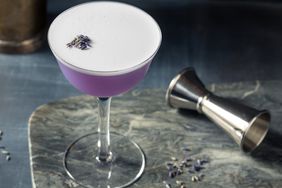 lavender cocktail with measuring jigger on a marble cutting board