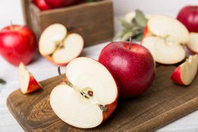 Fresh red apples with green leaves on table