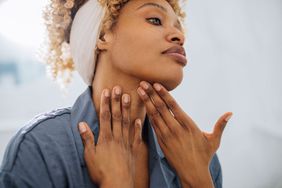 woman examining skin on face for acne