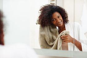 woman adding product to hair looking in mirror