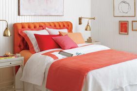 Color blocked bedroom with coral headboard and gold wall sconces