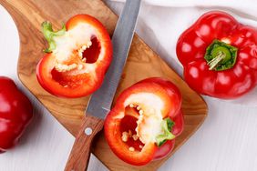 red bell pepper cut in half on cutting board with knife