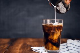 glass of iced coffee with milk being poured into it