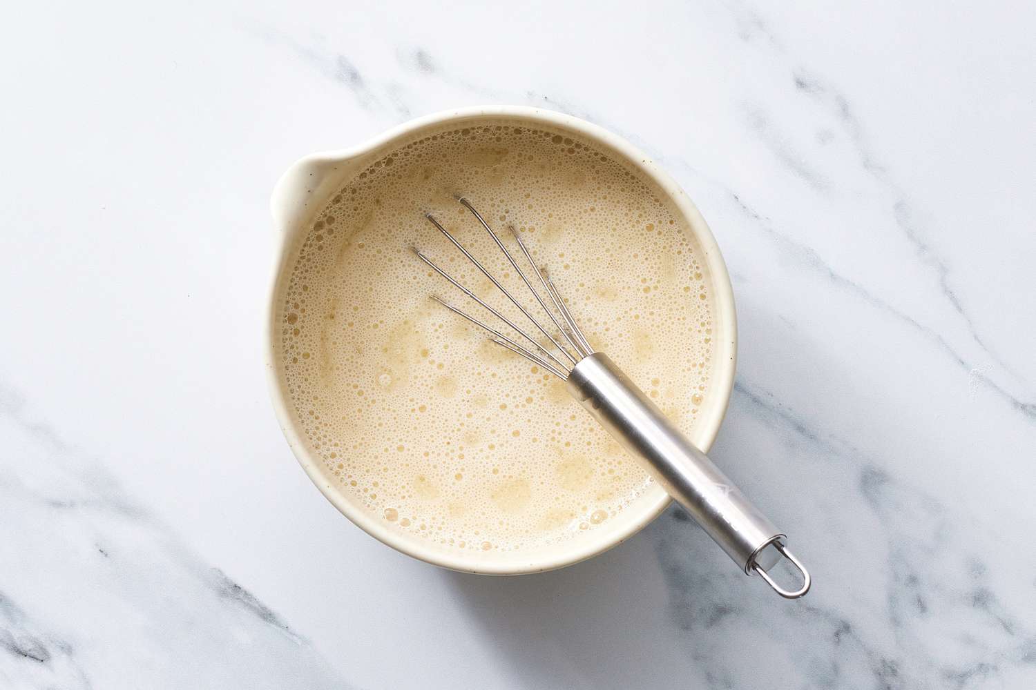 Milk in bowl with whisk for vegan pancakes