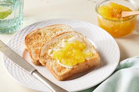 two pieces of toast with pineapple jam on it and glass container of jam