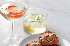 two aperitif cocktails with shrimp skewers on a marble surface