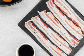 uncooked beef bacon on a board with other breakfast foods