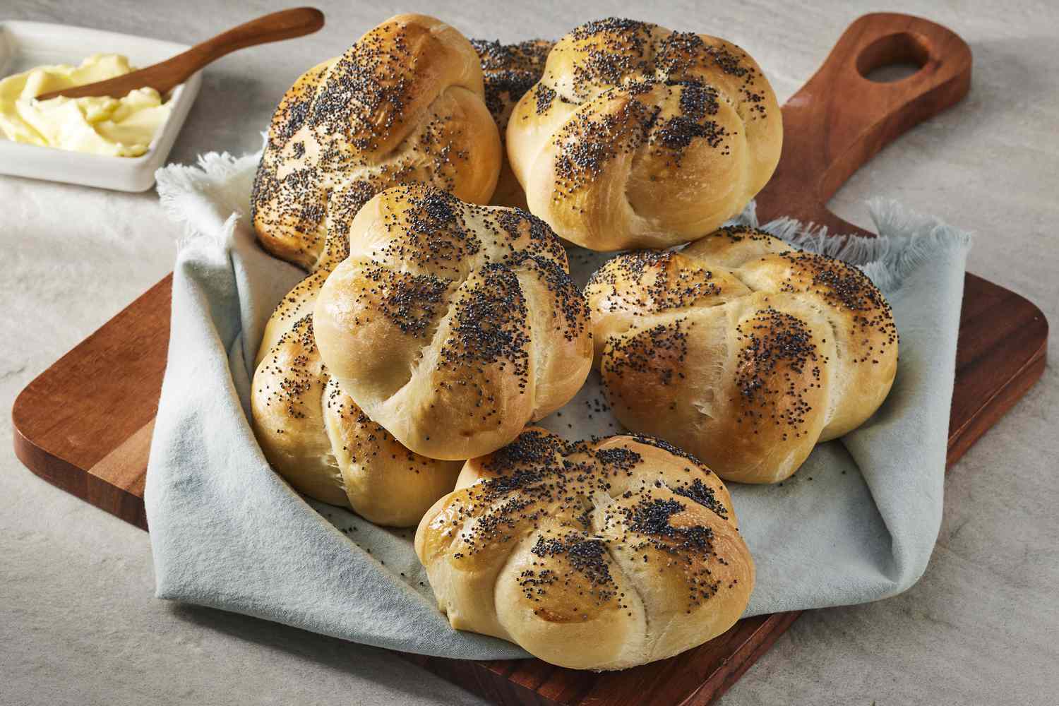 Kaiser rolls on cutting board with butter in the background