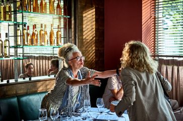 Senior woman welcoming friend in restaurant