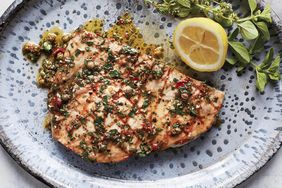 swordfish with sicilian oregano-caper sauce served on a blue speckled plate